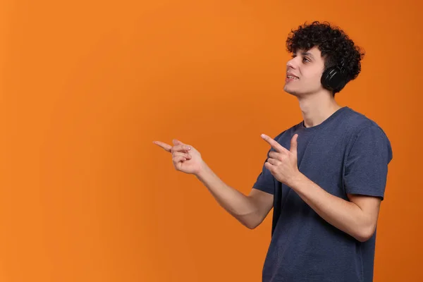 Schöner Junger Mann Mit Kopfhörern Der Auf Etwas Auf Orangefarbenem — Stockfoto