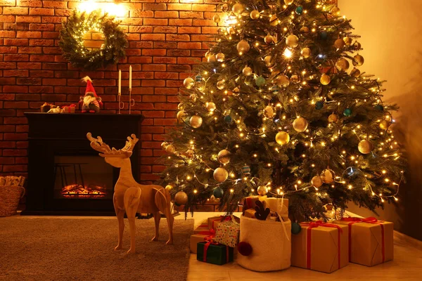 リビングルームでお祝いのライト 木製の鹿やクリスマスプレゼントと美しい木 インテリアデザイン — ストック写真