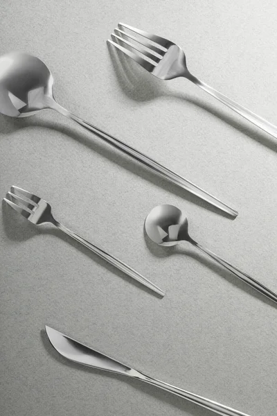 灰色の背景にフォーク ナイフ スプーン フラットレイアウト おしゃれなカトラリーセット — ストック写真