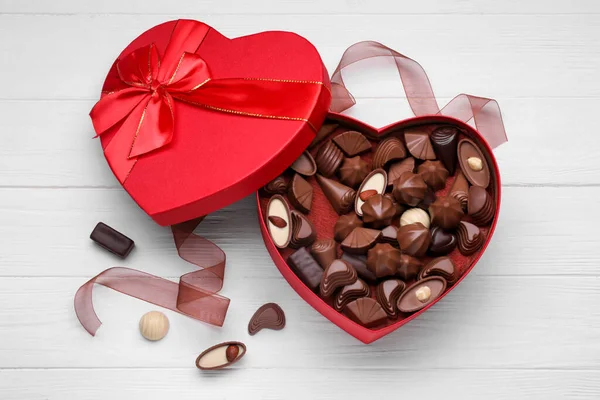 心形盒子 白色木制桌子上有美味的巧克力糖果和丝带 — 图库照片