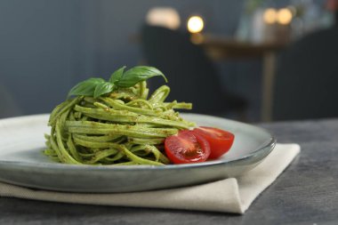 Restoranda gri masada servis edilen ıspanaklı ve domatesli tagliatelle, yakın plan. Makarna yemeğinin enfes sunumu