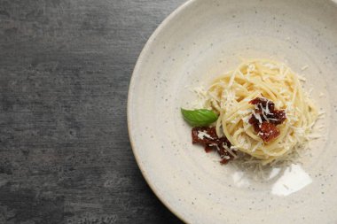 Gri masada güneşte kurutulmuş domatesli ve parmesan peynirli leziz spagetti, üst manzara ve yazı için yer. Makarna yemeğinin enfes sunumu