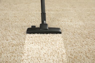 Elektrikli süpürgeyle halı süpürüyorum. Kirli yüzeyde temiz iz