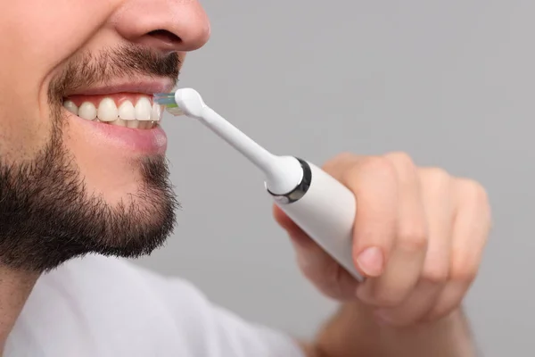 Mann Beim Zähneputzen Mit Elektrischer Zahnbürste Auf Hellgrauem Hintergrund Nahaufnahme — Stockfoto