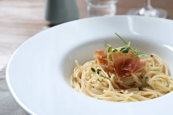 stock image Tasty spaghetti with prosciutto and microgreens on plate, closeup. Exquisite presentation of pasta dish