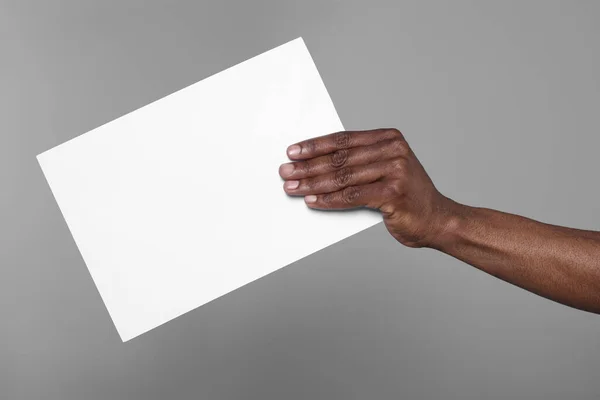 African American Man Holding Sheet Paper Grey Background Closeup Mockup — Foto de Stock