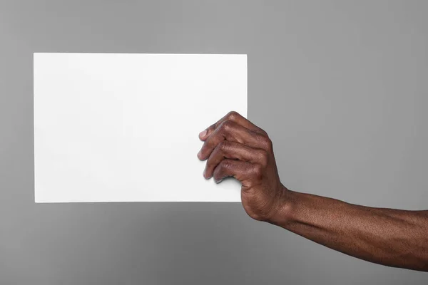 African American Man Holding Sheet Paper Grey Background Closeup Mockup — Photo