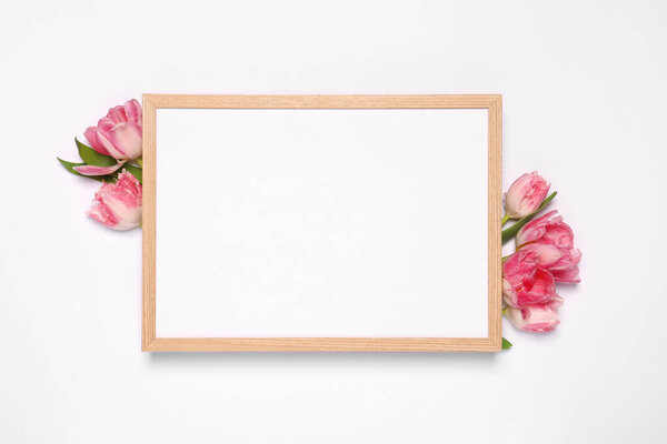 Empty photo frame and beautiful tulip flowers on white background, flat lay. Mockup for design