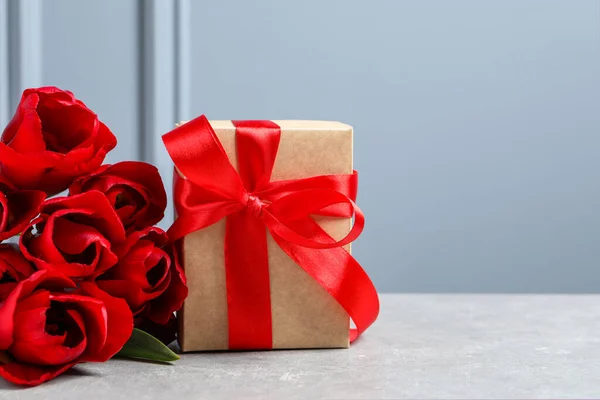 Piękne Pudełko Kokardą Czerwonymi Kwiatami Tulipanów Jasnym Stole Miejsce Tekst — Zdjęcie stockowe
