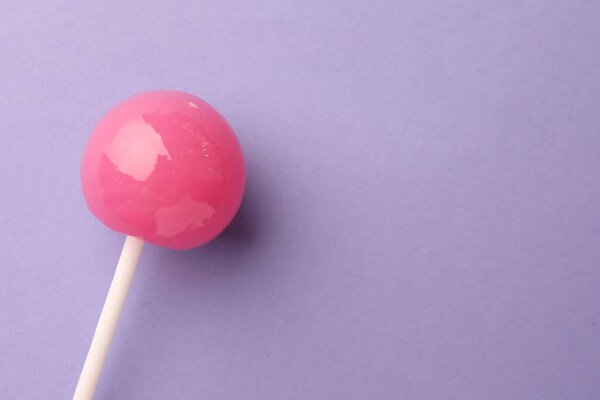 Tasty lollipop on violet background, top view. Space for text