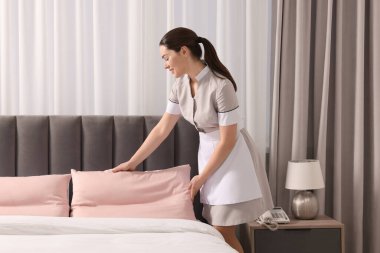 Genç hizmetçi otel odasında yatak yapma