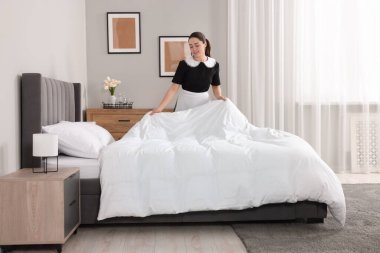 Otel odasında yatak yapma genç Oda hizmetçisi