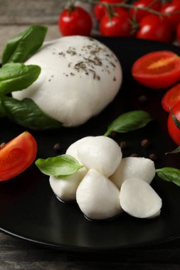 Domatesli ve fesleğenli lezzetli mozzarella ahşap masada, yakın plan.