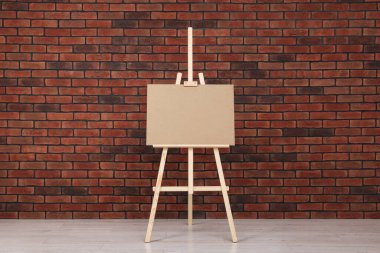 Kapalı alandaki tuğla duvarın yanında boş tahta sehpa.