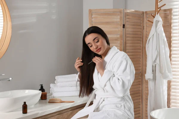 若い女性がバスルームで髪にエッセンシャルオイルを適用 — ストック写真