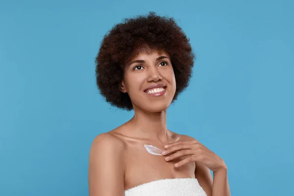 Mooie Jonge Vrouw Aanbrengen Crème Lichaam Licht Blauwe Achtergrond — Stockfoto