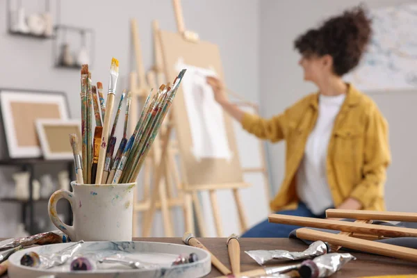 画架上的女人在画室里用纸作画 专注于画笔 — 图库照片