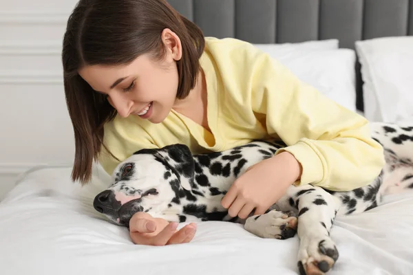 自宅でベッドの上に彼女の愛らしいダルマチアの犬と美しい女性 可愛いペット — ストック写真
