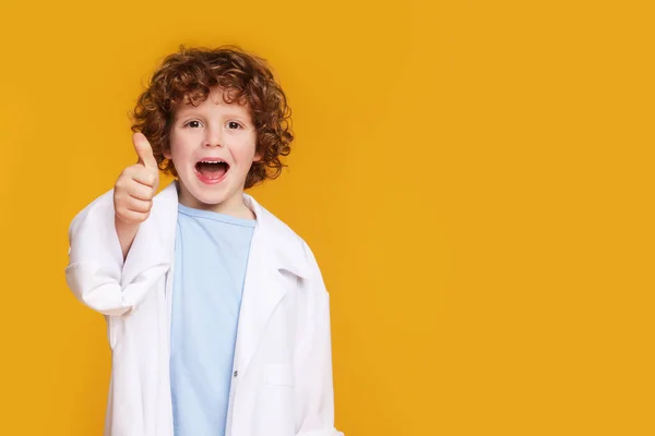 Malý Chlapec Lékařské Uniformě Ukazuje Palec Nahoru Žlutém Pozadí Mezera — Stock fotografie