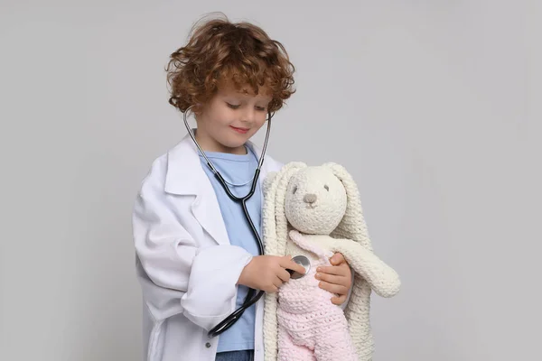 Küçük Çocuk Açık Gri Arka Planda Oyuncak Tavşanla Doktorculuk Oynuyor — Stok fotoğraf
