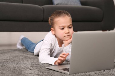 Evde dizüstü bilgisayar kullanan küçük bir kız. İnternet bağımlılığı