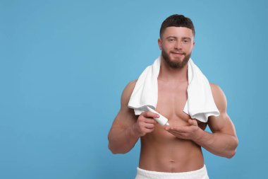 Açık mavi arkaplana vücut kremi süren yakışıklı adam, metin için boşluk