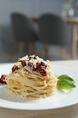 Restorandaki ahşap masada güneşte kurutulmuş domatesli ve parmesan peynirli leziz spagetti, yakın plan. Makarna yemeğinin enfes sunumu