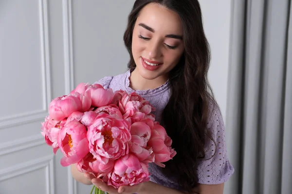 ピンクの牡丹の花束と美しい若い女性屋内 — ストック写真