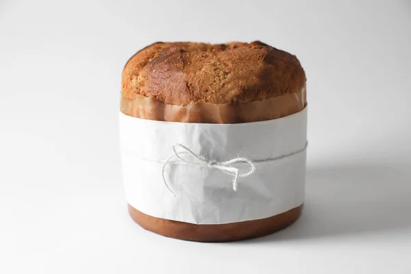 Delicious Panettone cake wrapped in parchment paper on white background. Traditional Italian pastry