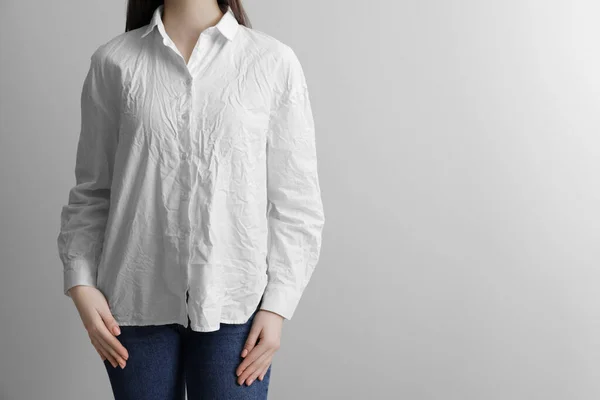 stock image Woman wearing wrinkled white blouse on light grey background, closeup. Space for text