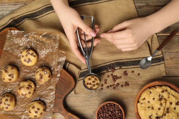 stock image Woman making delicious chocolate chip cookies at wooden table, top view