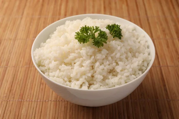 Schüssel Mit Köstlichem Reis Und Petersilie Auf Bambusmatte — Stockfoto