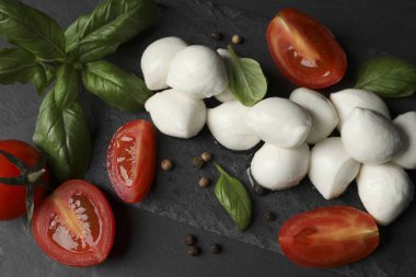 Lezzetli mozzarella topları, domatesler ve fesleğen yaprakları siyah masada, düz yatıyordu.