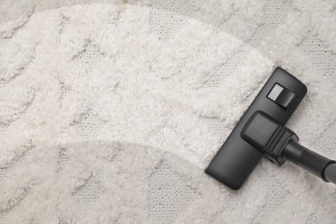 Elektrikli süpürgeyle halı süpürüyorum, üst görüş ve mesaj için yer açıyorum. Kirli yüzeyde temiz iz