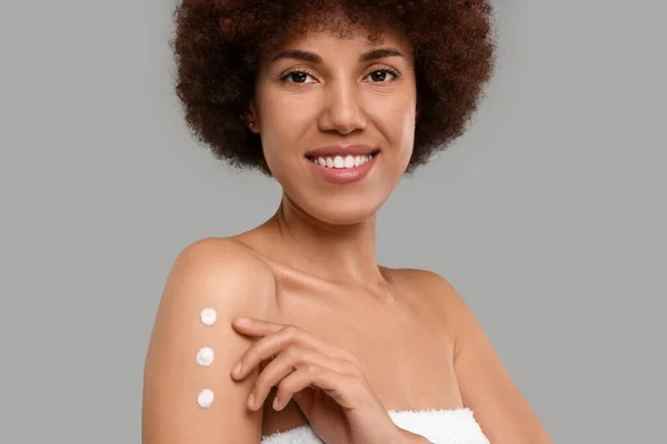 Mooie Jonge Vrouw Aanbrengen Lichaam Crème Arm Grijze Achtergrond — Stockfoto