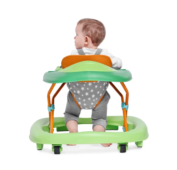 Cute little boy making first steps with baby walker on white background, back view