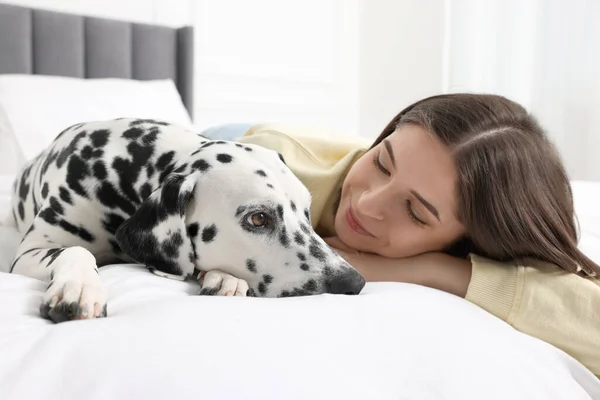 漂亮的女人和她可爱的达尔马提亚犬躺在床上可爱的宠物 — 图库照片