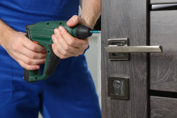 ドアロックを屋内で修理ネジ銃と一致する労働者 クローズアップ — ストック写真