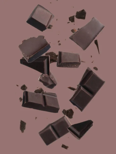 Κομμάτια Σοκολάτας Που Πέφτουν Ανοιχτό Καφέ Φόντο — Φωτογραφία Αρχείου