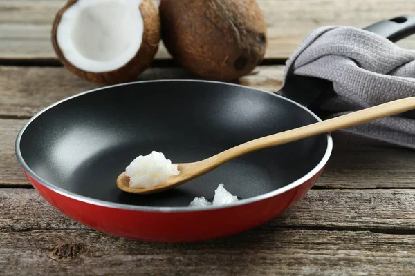 stock image Frying pan with organic coconut cooking oil and spoon on wooden table, closeup