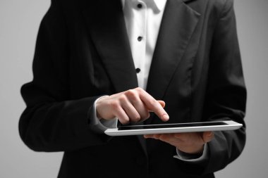 Gri arka planda modern tablet kullanan kadının yakın görüntüsü