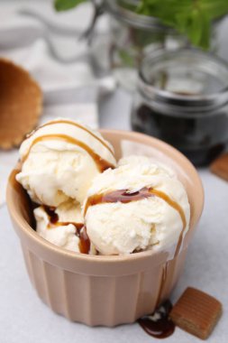 Karamel soslu dondurma ve açık gri masada şekerleme. Yakın plan.