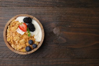 Lezzetli gevrek mısır gevreği, yoğurt ve ahşap masada taze böğürtlen, yazı için yeri olan üst manzara. Sağlıklı kahvaltı.