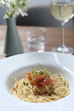 Prosciutto ve mikroyeşillikli lezzetli spagetti ahşap masada servis edilir, yakın plan. Makarna yemeğinin enfes sunumu