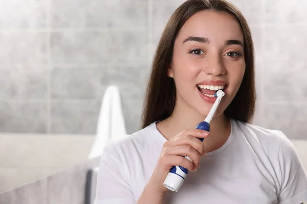 Młoda Kobieta Myje Zęby Elektryczną Szczoteczką Zębów Łazience — Zdjęcie stockowe