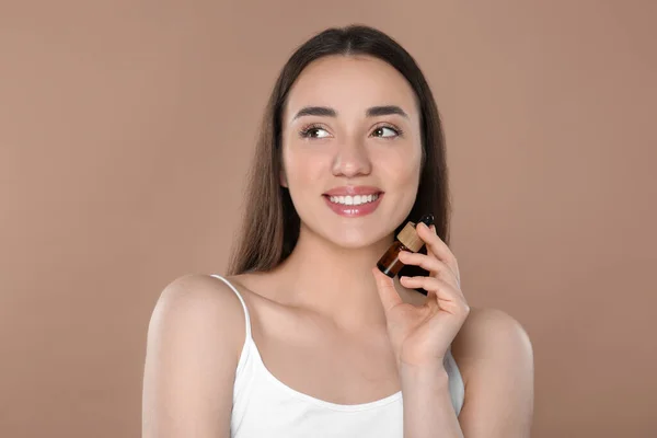 Mooie Jonge Vrouw Met Fles Etherische Olie Bruine Achtergrond — Stockfoto