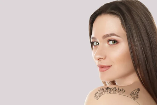 Leende Ung Kvinna Med Tatuering Blomma Och Fjäril Ljus Bakgrund — Stockfoto