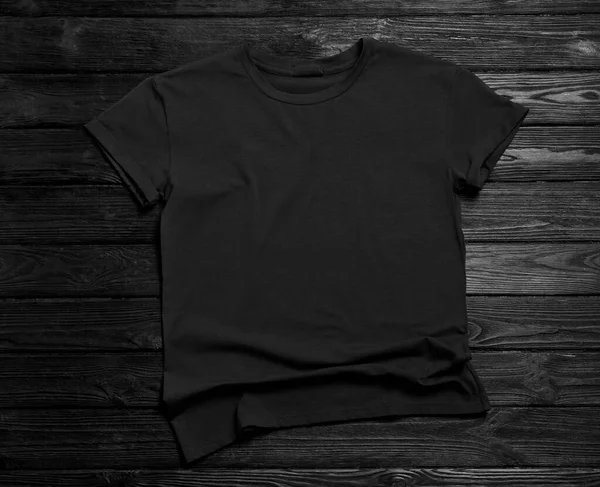 黒の木の背景にスタイリッシュなTシャツ トップビュー — ストック写真