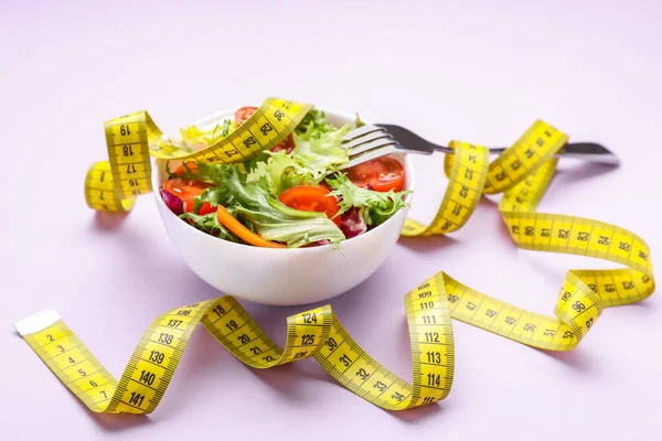 新鮮な野菜サラダをボウルに入れ 紫色の背景にテープをフォークして測定します 健康的な食事のコンセプト — ストック写真