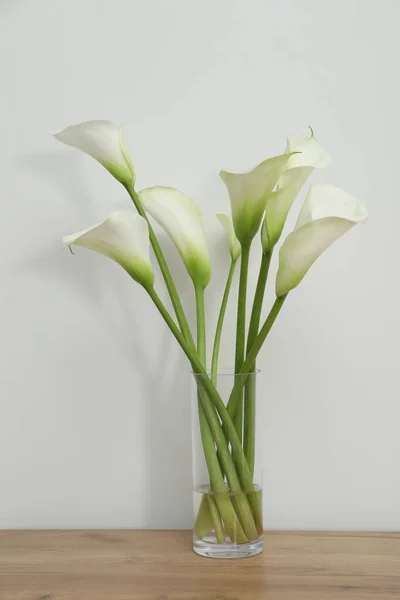 Schöne Calla Lilienblüten Glasvase Auf Holztisch Neben Weißer Wand — Stockfoto